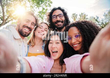 Group of multiracial young people smiling and taking a selfie together. Close up portrait of happy asian teenage woman laughing with his cheerful friends. Classmates having fun on friendly meeting. High quality photo Stock Photo
