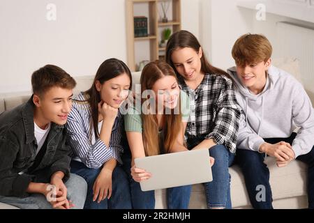 Group of happy teenagers using laptop in room at home Stock Photo