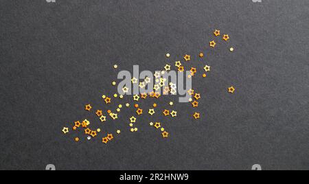Many beautiful star shaped sequins on black background, flat lay Stock Photo