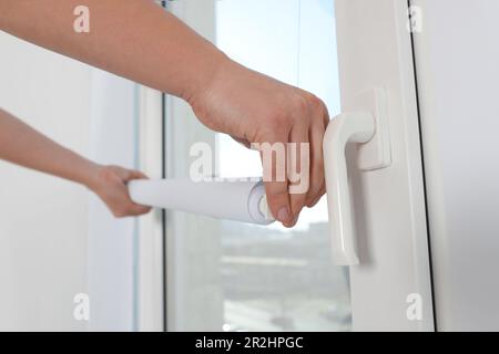 Man installing roller window blind indoors, closeup Stock Photo
