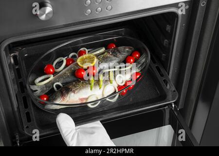 Glass baking tray with raw sea bass fish and ingredients in oven, closeup  Stock Photo - Alamy