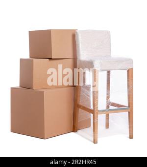 Chair wrapped in stretch film and boxes on white background Stock Photo