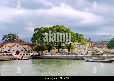 old warehouses and fishing boats under dark cloudy sky at Ana Chavez Bay in Sao Tome on Sao Tome Island in West Africa Stock Photo