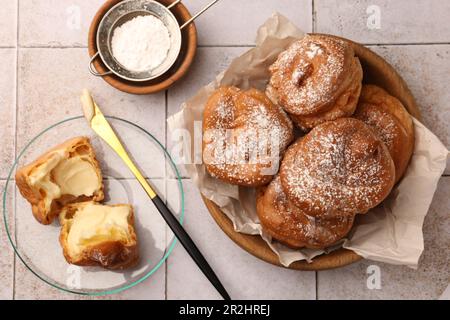 Delicious profiteroles filled with cream on white tiled table, flat lay Stock Photo