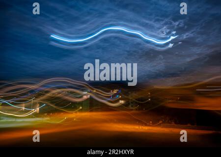 Long Exposure on a City with Light Trails and Moon and Sky With Clouds in Caslano, Ticino, Switzerland. Stock Photo