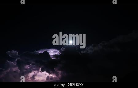 Beautiful Lightning and Full Moon and Clouds at Night in Lugano, Ticino, Switzerland. Stock Photo
