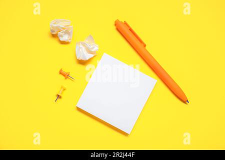 Pen with sticky notes and pins on yellow background Stock Photo