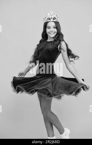 Movement windy dress. Portrait of ambitious teenage girl with crown, feeling princess, confidence. Child princess crown on isolated studio background. Stock Photo