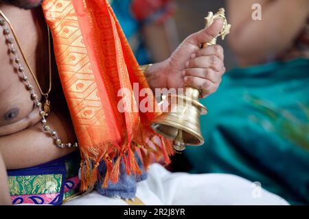 Hand holding ceremonial bell, Sri Srinivasa Perumal Hindu temple, Hindu priest (Brahmin) performing puja ceremony and rituals, Singapore Stock Photo