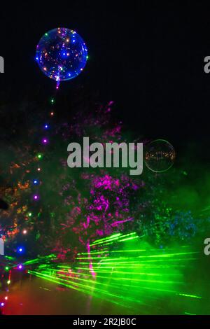 Colorful laser show with balloons and illuminated trees Stock Photo
