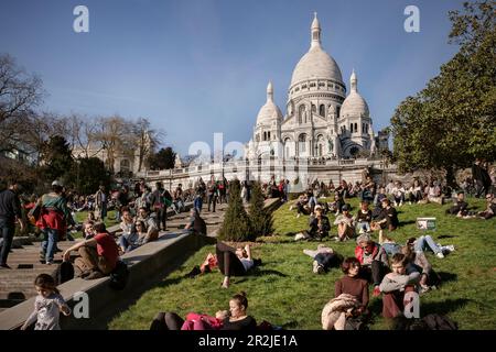 Crowds of people relaxing on the grassy areas in front of the Basilica &quot;Sacré-Cœur de Montmartre&quot;, Capital Paris, Ile-de-France, France Stock Photo