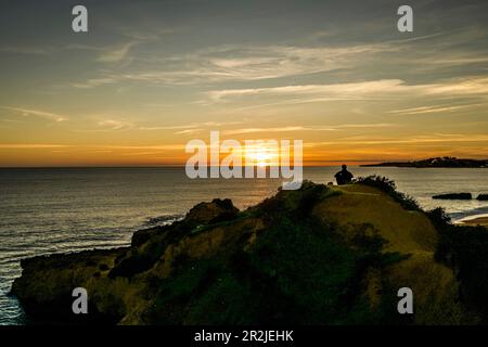 Hikers on the cliff watching the sunset over the sea at Albufeira, Algarve, Portugal Stock Photo