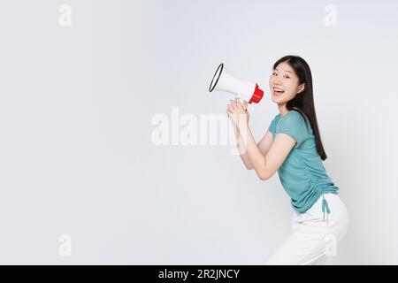 Young woman holding megaphone isolated on white background. Stock Photo