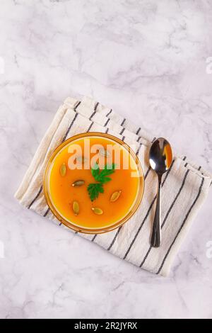 Creamy pumpkin soup with a smooth texture, served on a marble background with empty space for additional elements. Stock Photo