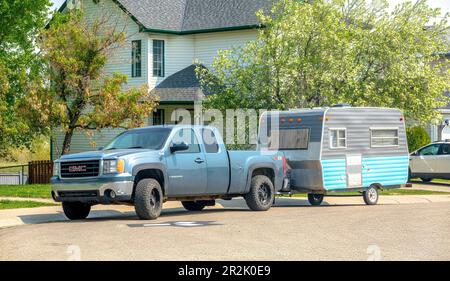 Calgary, Alberta, Canada. May 18, 2023. A blue Truck with a vintage camping trailer RV. Stock Photo