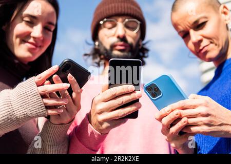three young friends using mobile phones Stock Photo