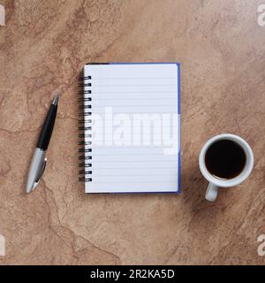 Cup of coffee and opened notebook with pen on stone background, top view Stock Photo