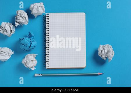 Notebook and paper balls on blue background, top view Stock Photo