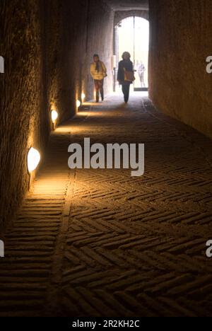 blurred people walking in underground city of Napoli, Italy (foucs on terracotta floor herringbone) Stock Photo