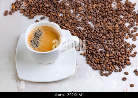 A white cup of black coffee on a background of roasted beans. A picture for a coffee shop. Top view of a cup of coffee. Stock Photo