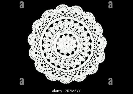 White hand made crocheted coaster lace doily on black background. Stock Photo