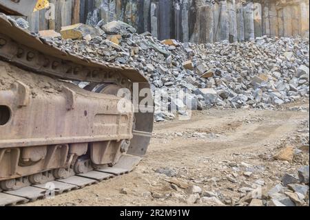 Excavator caterpillar in a basalt quarry. Extraction of basalt, granite. Excavators in a basalt quarry near the forest. Large excavator in an open min Stock Photo