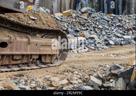 Excavator caterpillar in a basalt quarry. Extraction of basalt, granite. Excavators in a basalt quarry near the forest. Large excavator in an open min Stock Photo