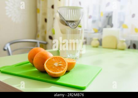Close-up of oranges on the background of a juicer. Preparing fresh orange juice in the kitchen. Stock Photo