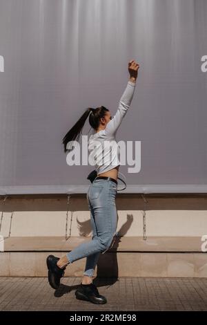 Fit brunette girl with ponytail dancing in front of the big wall Stock Photo