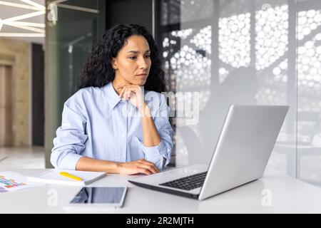 Beautiful indian woman programmer web developer focused and confident working on laptop writing code programming business woman worker in modern office working in casual clothes Stock Photo