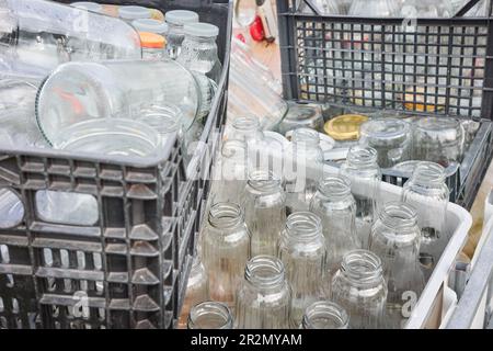 Used empty glass bottles stored in containers for recycling, selective focus. Stock Photo