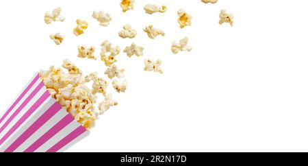 Popcorn flying out of pink white striped paper box isolated on white background with copy space. Splash, levitation of popcorn grains. Stock Photo