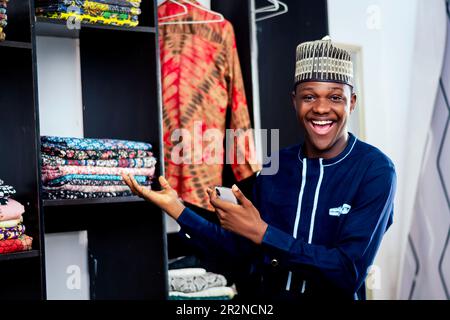 A black african man in a blue shirt is holding a cell phone Stock Photo