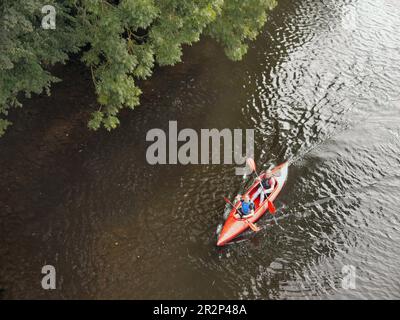 Two canoeists wave as they approach Hay Bridge on the River Wye, Powys, Wales, UK, in September 2019 Stock Photo