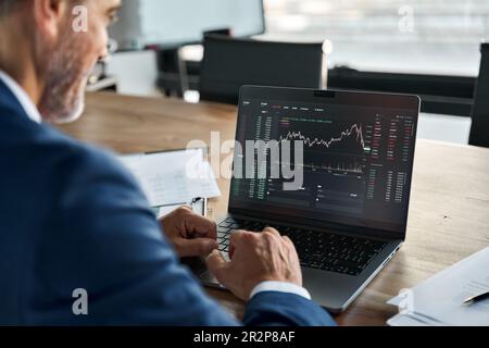 Stock market Investor analyzing crypto market on computer screen. Over shoulder Stock Photo
