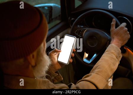 Older man driver sitting in driving car van using apps mobile phone. Mock up Stock Photo