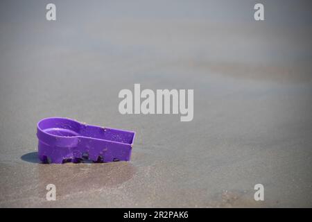 abandoned purple bucket on the sand at the beach, not being played with, copy space Stock Photo