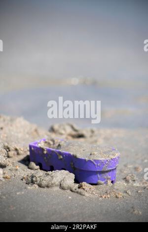 abandoned purple bucket on the sand at the beach, not being played with, copy space Stock Photo