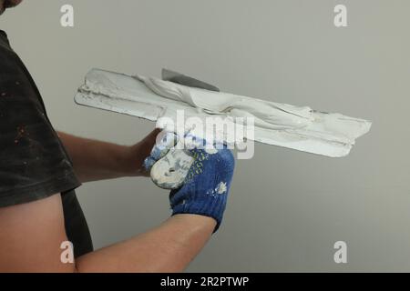 Professional worker putting plaster on putty knife indoors, closeup Stock Photo