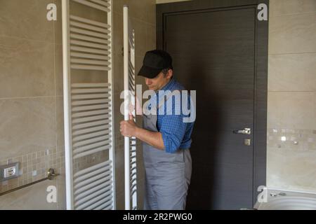 Image of a plumber while he is assembling a radiator like a towel warmer in a bathroom at home. Stock Photo