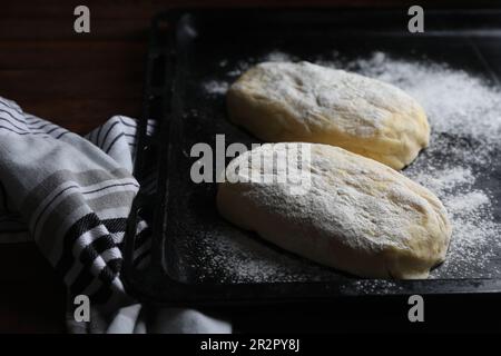 Raw dough for ciabatta and flour on wooden table Stock Photo