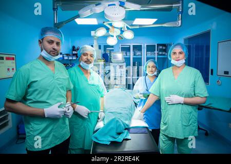 Team of Indian surgeons medical staff wearing mask and and cap looking at camera after successfully performed surgery in operation theater at hospital Stock Photo