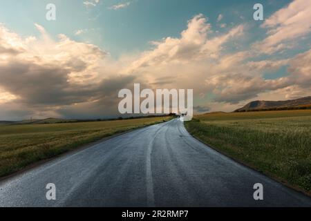 clearing up of dramatic sky after the rain on rural road of Sicily at the sunset in Italy Stock Photo
