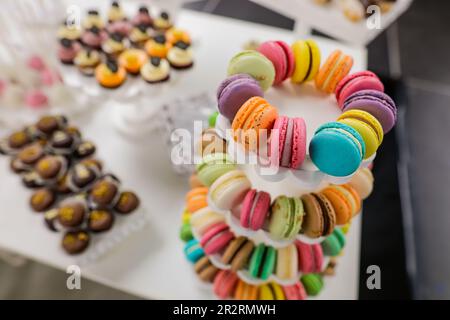 Shallow depth of field (selective focus) details with multicoloured macaroons on a table filled with candy. Stock Photo