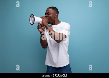 charming young african man in white t-shirt with loudspeaker on studio background with copy space Stock Photo