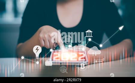 2022 and Startup concept with icon business and network connection on modern virtual interface from digital tablet.woman Touching tablet and graph Scr Stock Photo