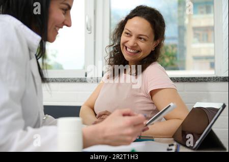 Doctor gynecologist discusses with pregnant woman a baby ultrasound scan, examines gravid patient, prescribea medicines Stock Photo