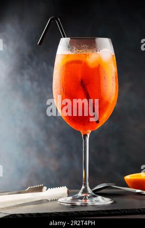 Aperol spritz cocktail and steel bar tools on slate board. Cocktail Aperol Spritz with black straw Stock Photo