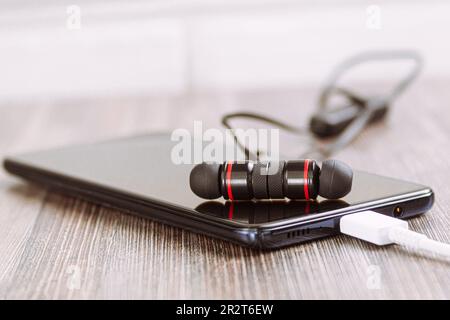 Black headphones and phone. View from the side. Macro photo, close-up. Bokeh Copy space Stock Photo