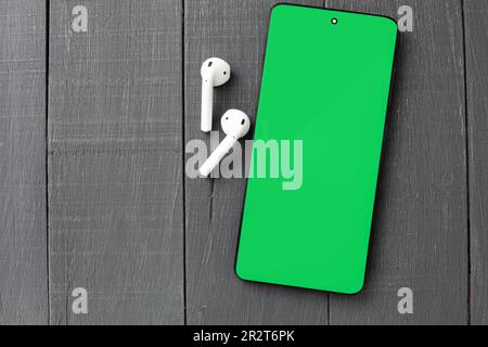 Mobile phone and headphones, close-up. Chromakey. Copy space. Close up of modern headphones on a portable phone holder Stock Photo